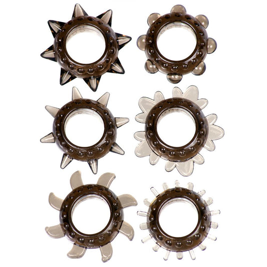 The Ticker 6 ring cock ring set. A set of 6 smoke black cock rings with different textures around the outside. One has thick spikes, one has thin spikes, one has blade-like fanned barbs, one has short thin sticks, one has wavy triple bump sections and one has smooth raised bubbles. All have a bumpy circumference.